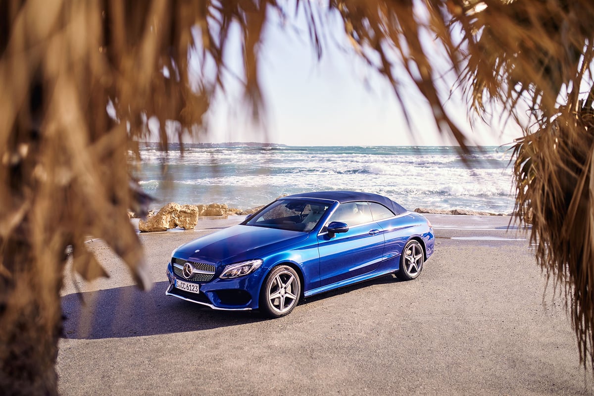 Blaues Mercedes C 400 Cabrio unter Palmen an der Strandpromenade von Barcelona