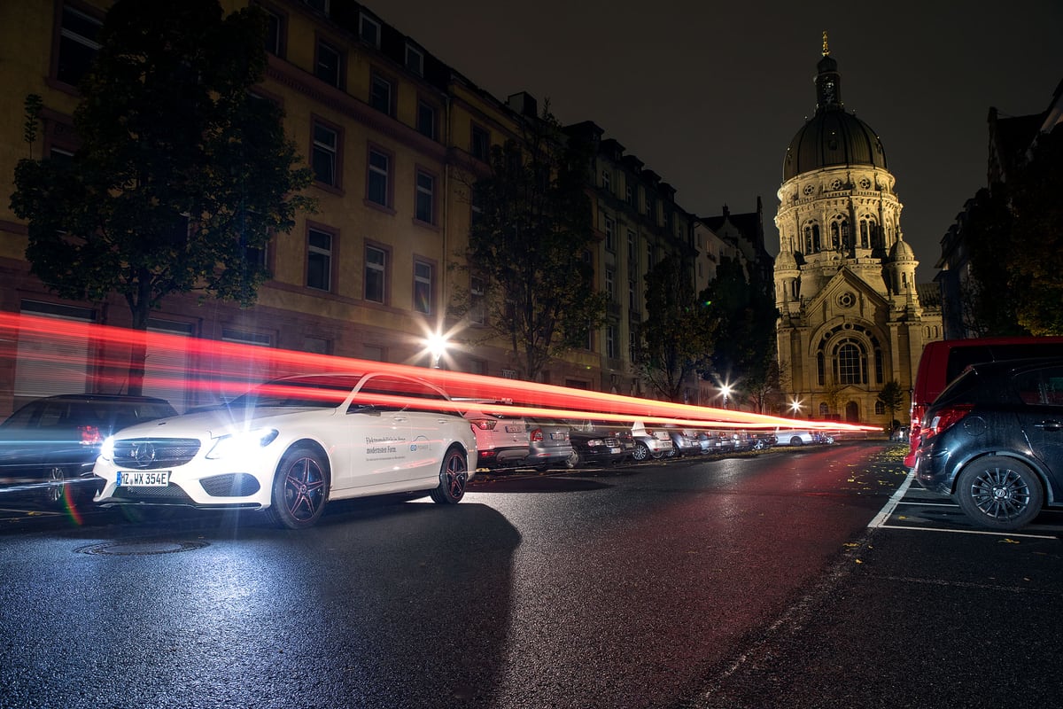 Mercedes CLA nachts in der Stadt mit Lichtspuren vorbeifahrender Autos