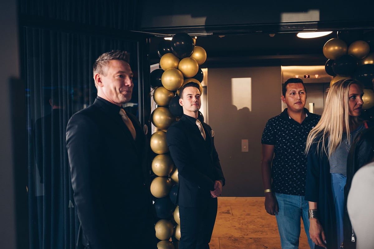 Gäste kommen durch einen mit goldenen Ballons dekorierten Eingang
