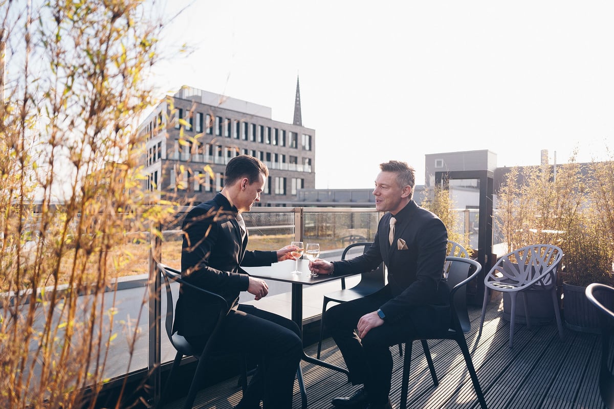 Zwei Männer im Gespräch an einem Tisch auf der Dachterrasse