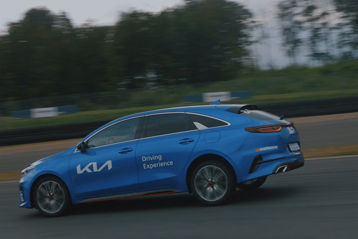 Blauer KIA mit Beklebung in Fahrt auf der Teststrecke