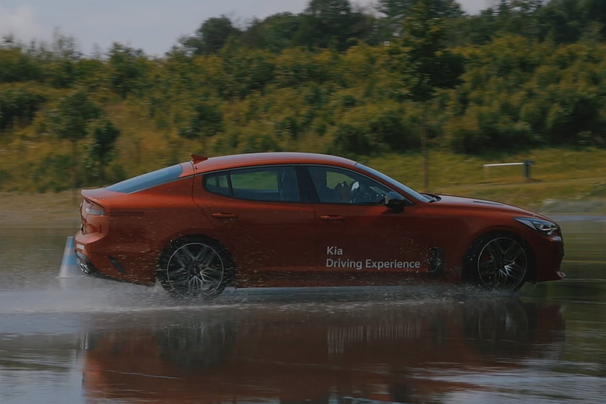Roter KIA in schneller Fahrt auf nasser Teststrecke – Driving Experience
