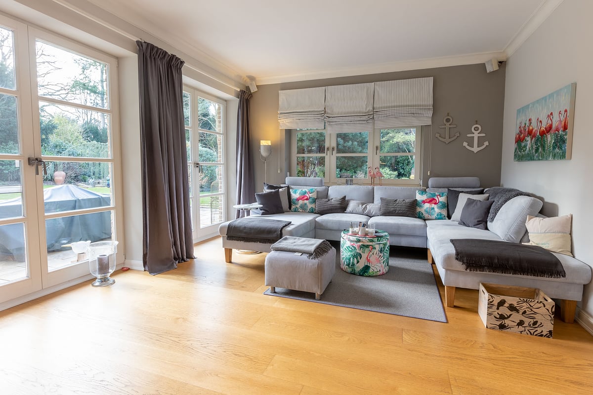 Wohnzimmer mit Ecksofa, Kamin und Blick in den Garten