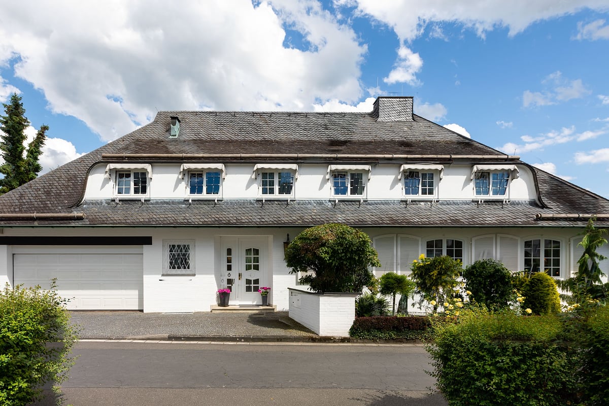 Weiße Villa mit Reetdach-Optik und Vorgarten