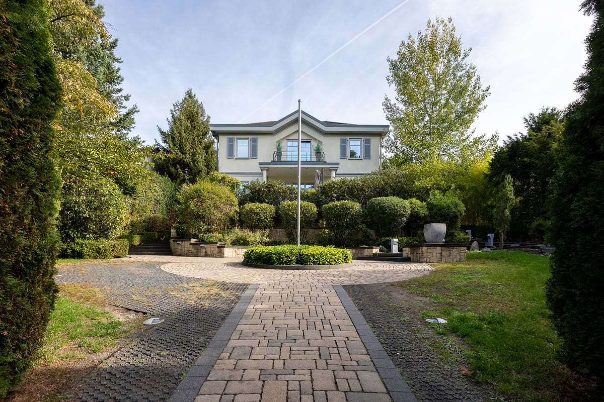 Außenansicht einer Villa mit gepflegtem Garten und Auffahrt