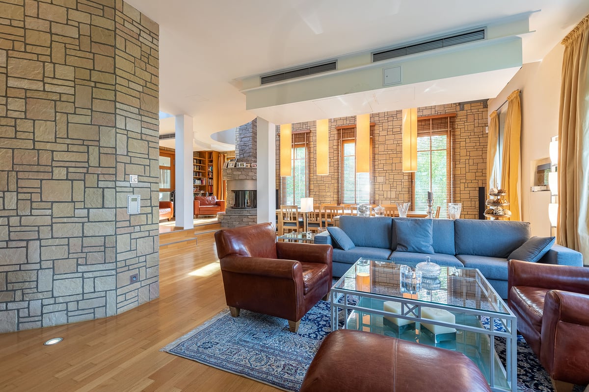 Großzügiges Wohnzimmer einer Villa mit Ledersofas, Natursteinkamin und Galerie