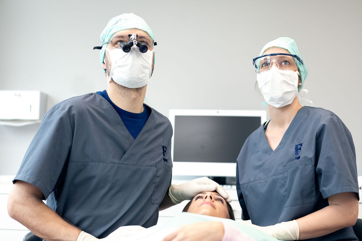 Behandlungsteam mit Lupenbrille und Mundschutz während einer Behandlung