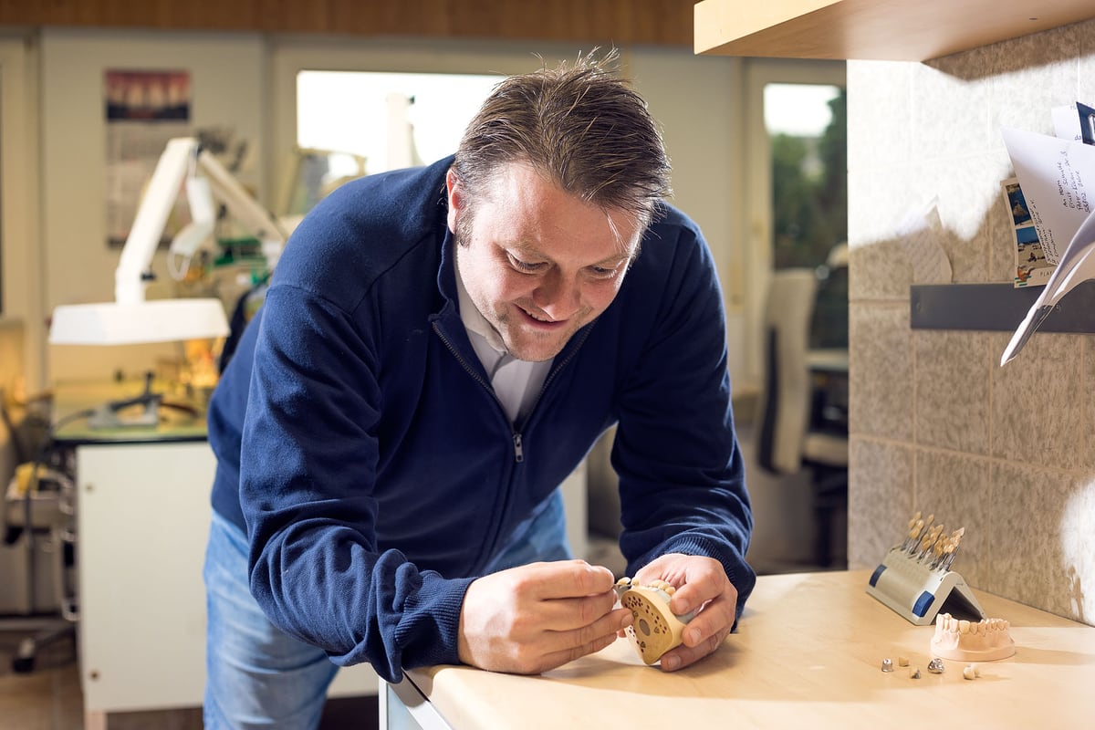 Zahntechniker arbeitet konzentriert an einem Modell in der Werkstatt